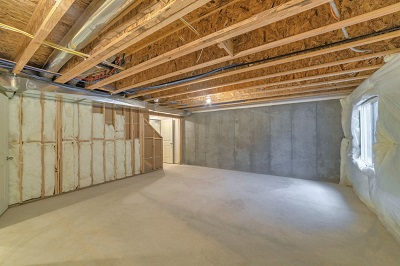 Basement floor that has been recently completed and still has wall studs and insulation exposed.