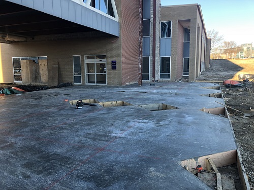 Large walking area outside of a college that has been freshly poured with concrete.