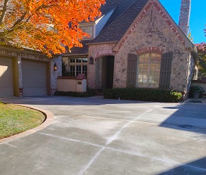Large house in the fall with a new concrete driveway and brick pattern outlining the edges