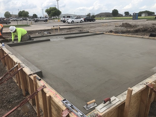 Freshly poured concrete slap that is being worked on by two people