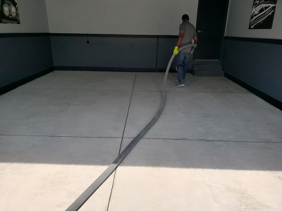 New garage floor that has a person vacuuming debris